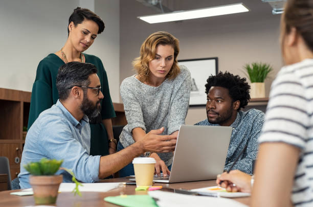 Busy multiethnic partners working together in a meeting room. Business people gathered to discuss some urgent matters. Group of creative businessmen and casual businesswomen discussing a new project in the office.
